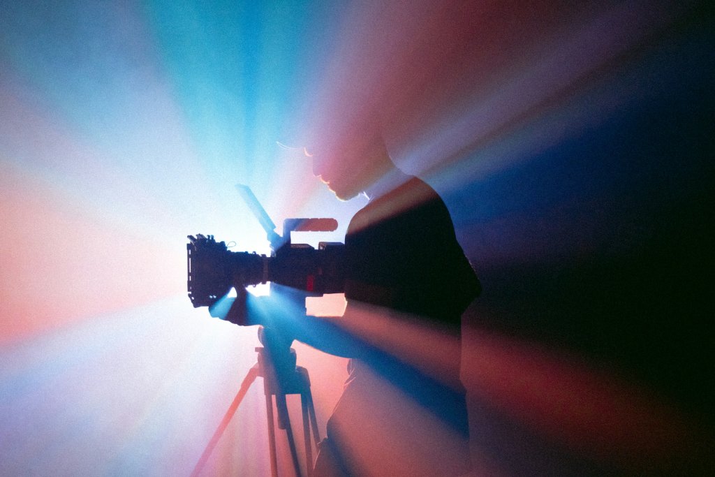 Silhouette of a videographer operating a professional camera in a cinematic video studio with dramatic lighting